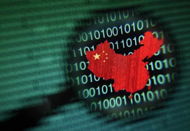 A map of China is seen through a magnifying glass on a computer screen showing binary digits in Singapore
